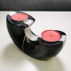 Black and white marble candle holder with two pink candles on a light surface.