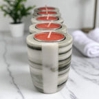 Marble-patterned candle holders with red candles on a marble surface.