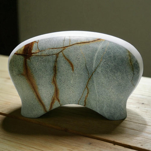 Marble-patterned stone object on a wooden surface with a blurred background