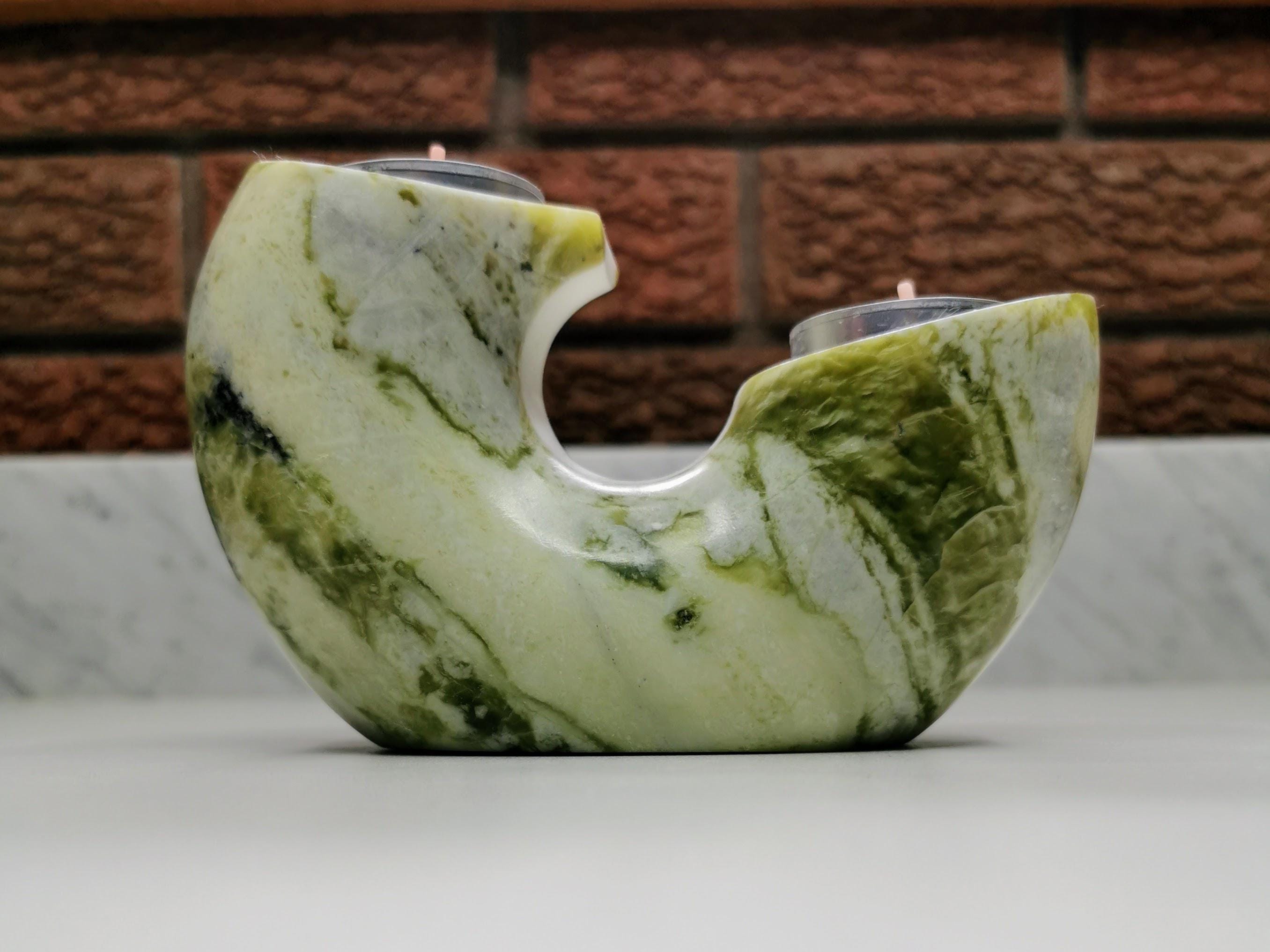 Marble-patterned candle holder with two candles against a brick wall background