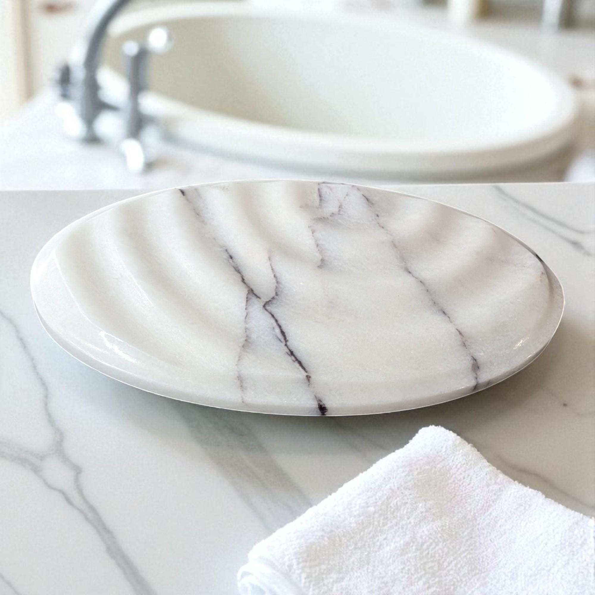Marble-patterned soap dish on a marble surface with a towel underneath.