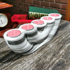 Marble-patterned candle holder with pink candles on a stone surface.