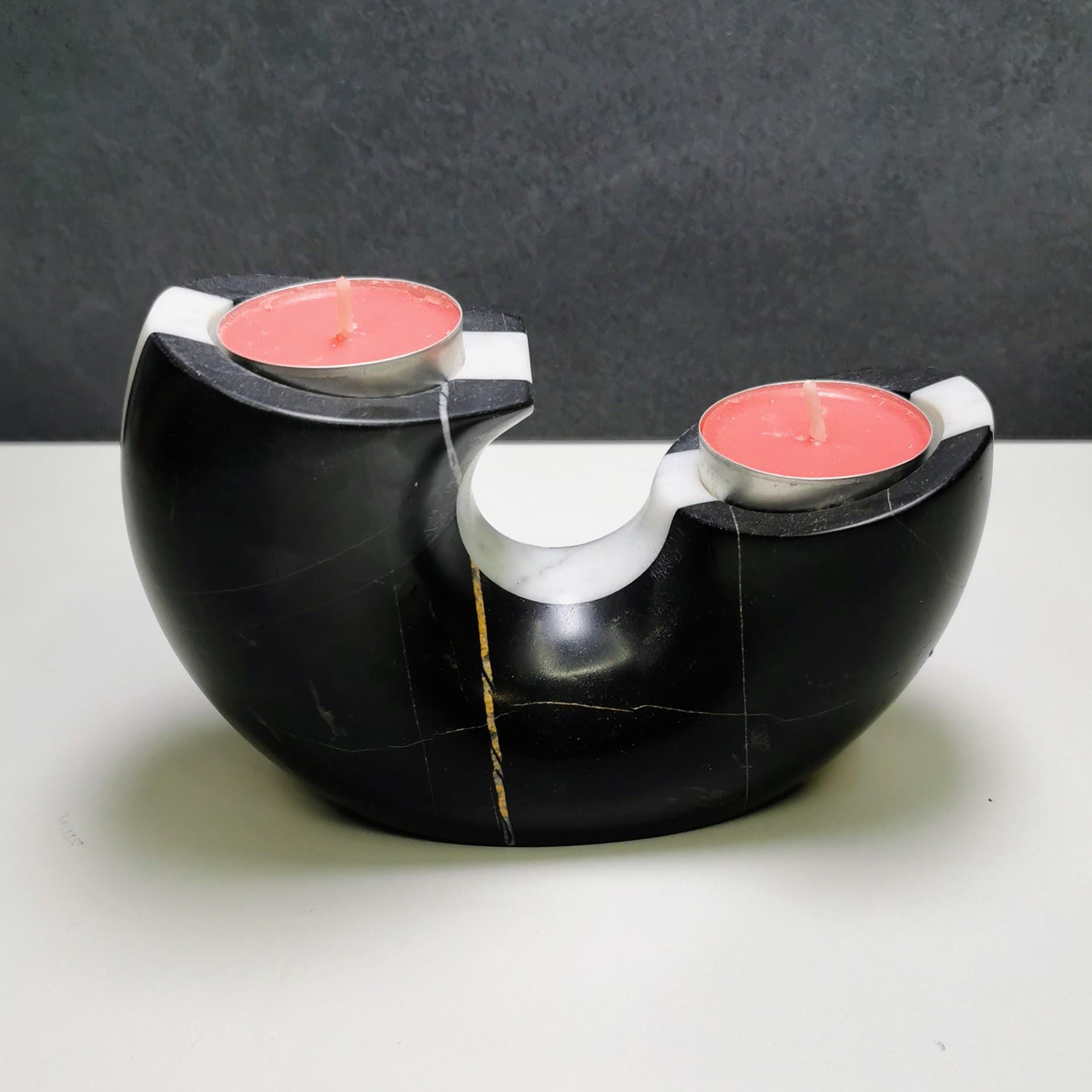 Black and white candle holder with pink candles on a gray background