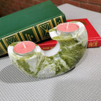 Green marble candle holder with pink candles on a textured surface