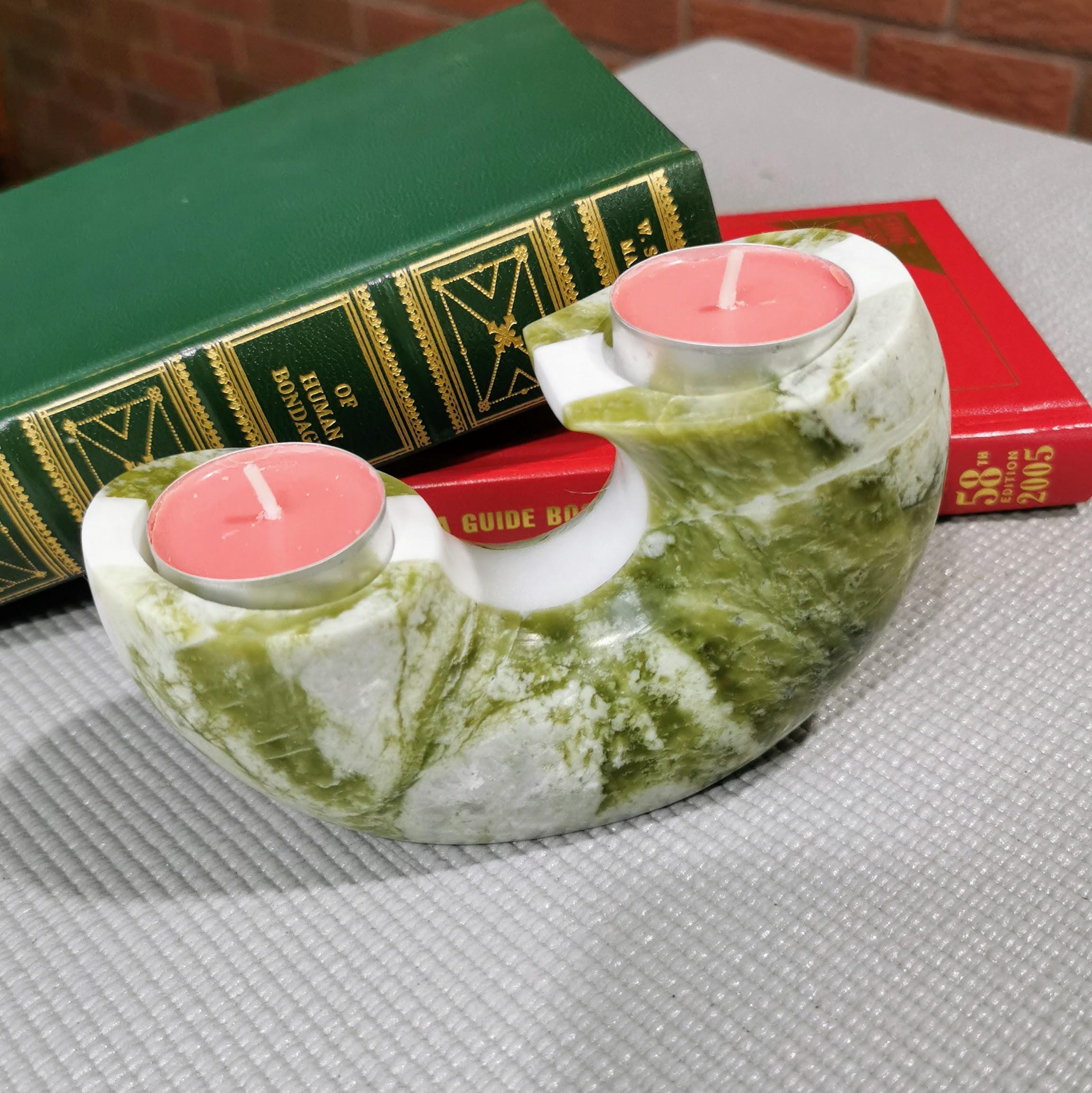 Green marble candle holder with pink candles on a textured surface