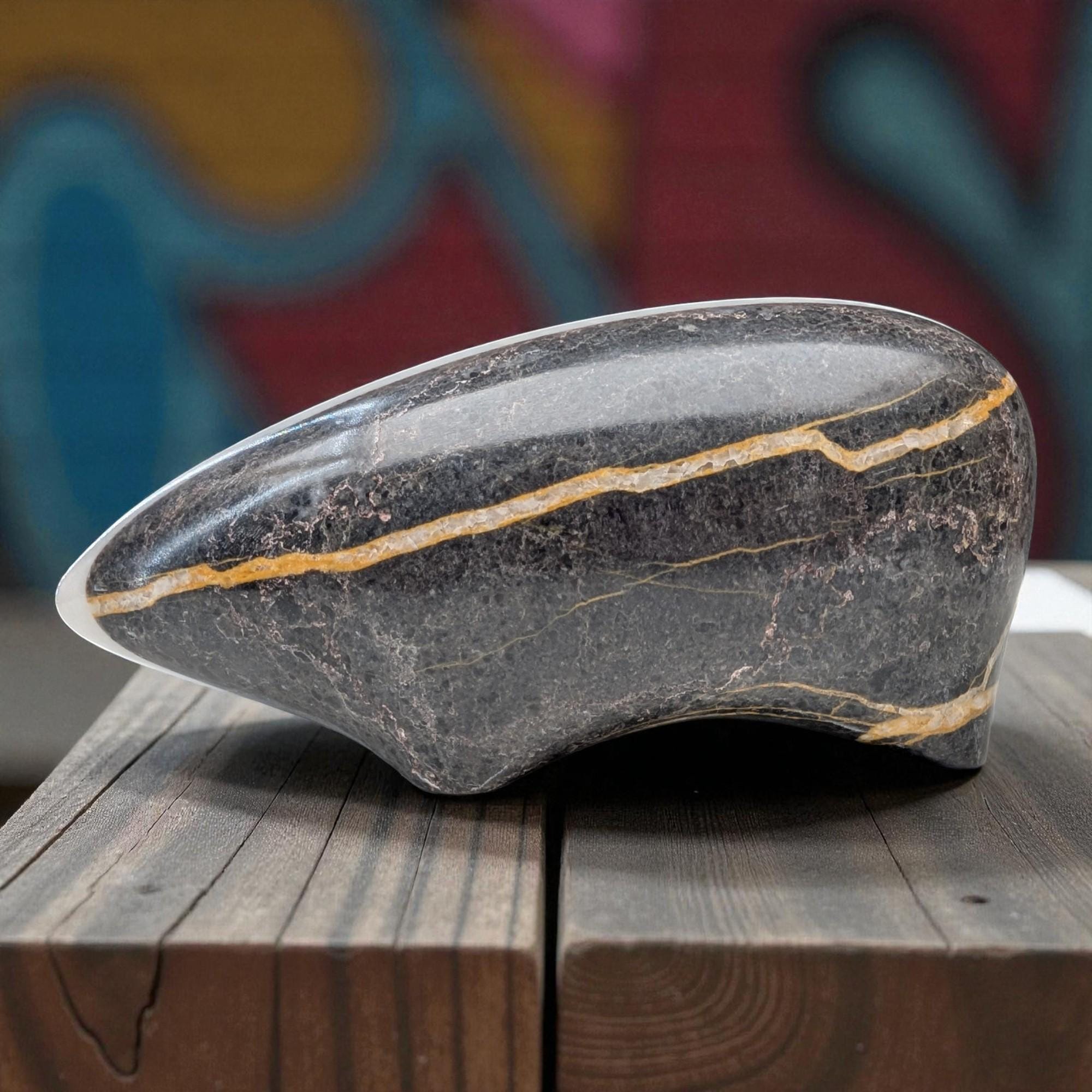 Decorative stone with a gold line on a wooden surface with a colorful abstract background