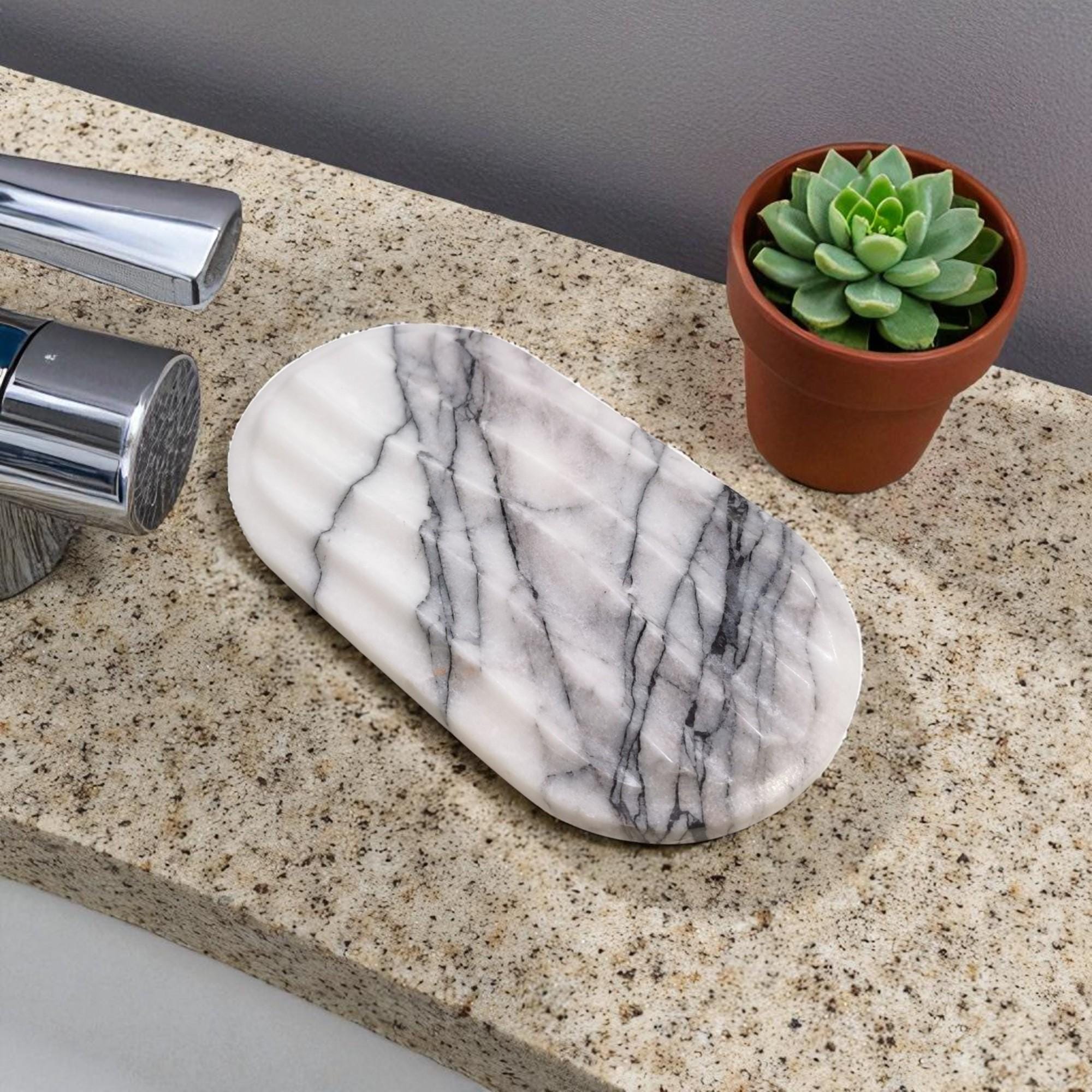 Marble-patterned soap dish on a bathroom counter with a potted succulent.
