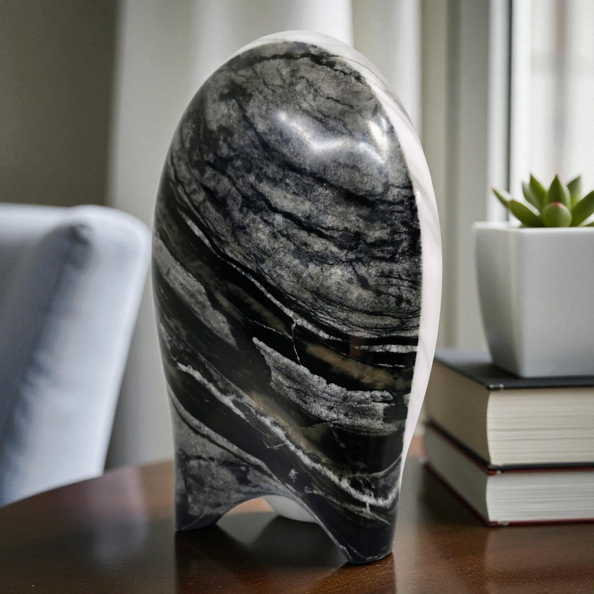 Marble-patterned object on a surface with books and a plant in the background