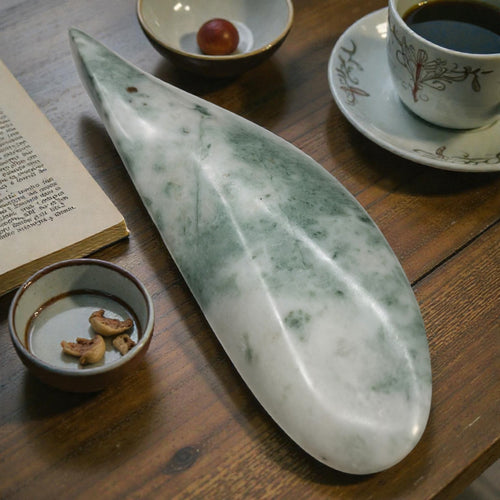 Marble-like stone on a wooden surface with a cup of coffee, book, and small bowl.