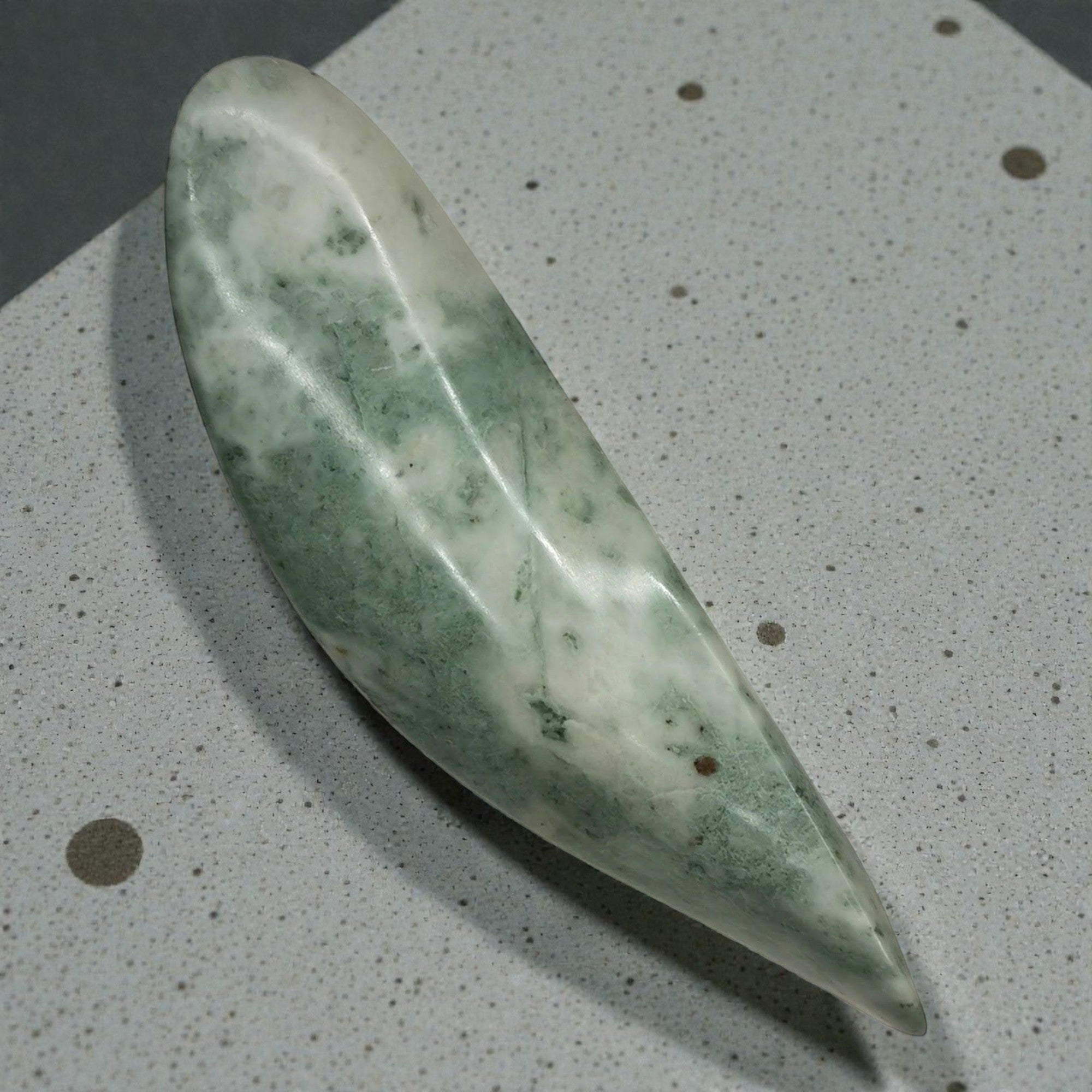 Green stone tool on a speckled gray surface