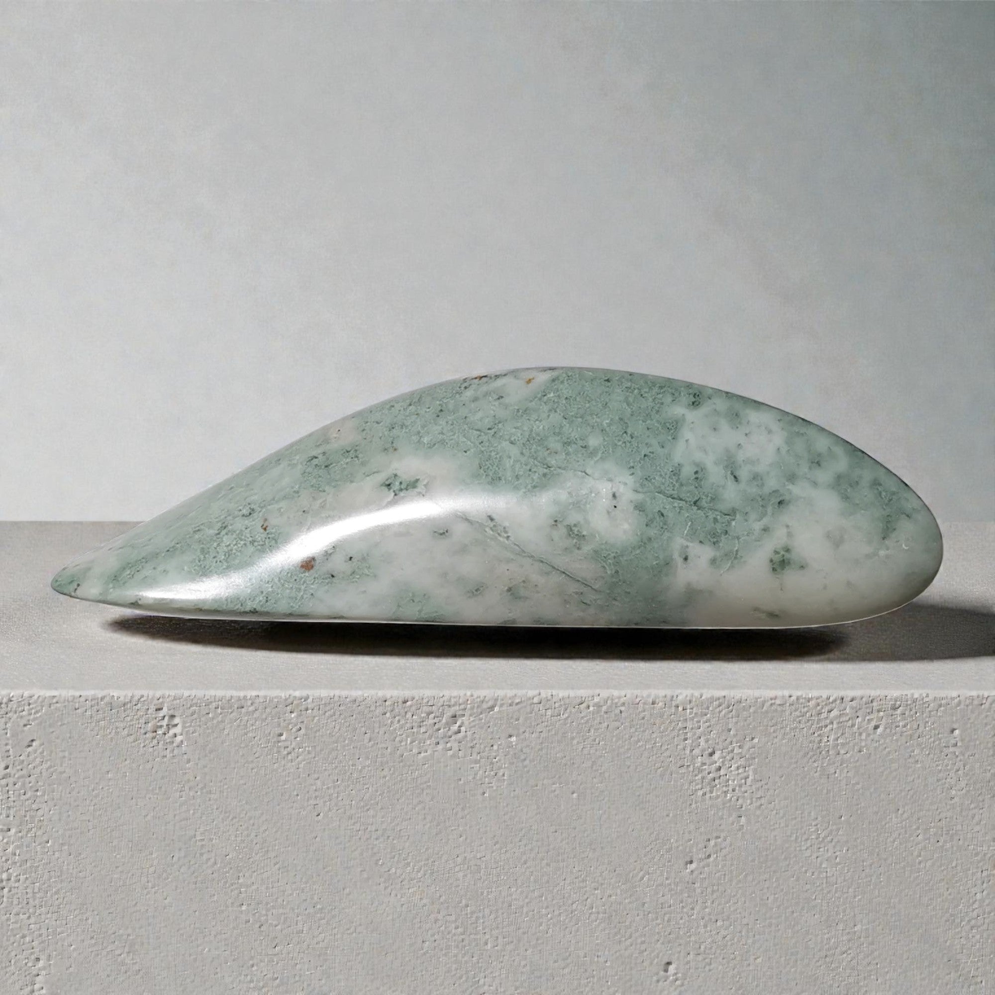 Green stone on a gray surface with a neutral background