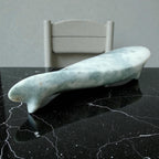 Marble-textured object on a black marble surface with a white chair in the background.