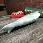 Green stone object on a wooden surface with books in the background