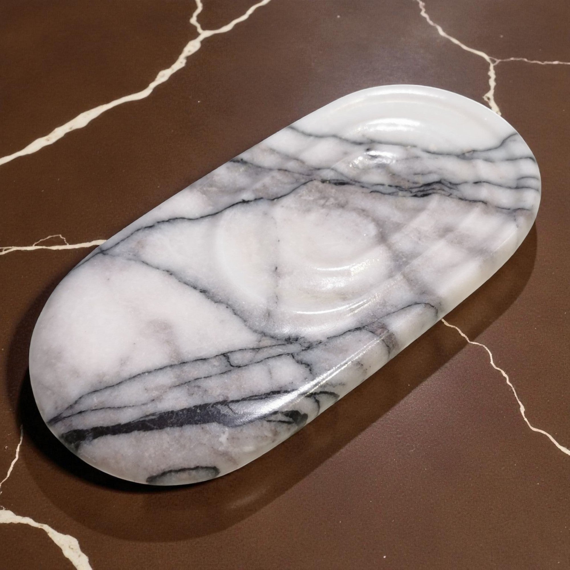 Marble-patterned oval object on a brown marble surface