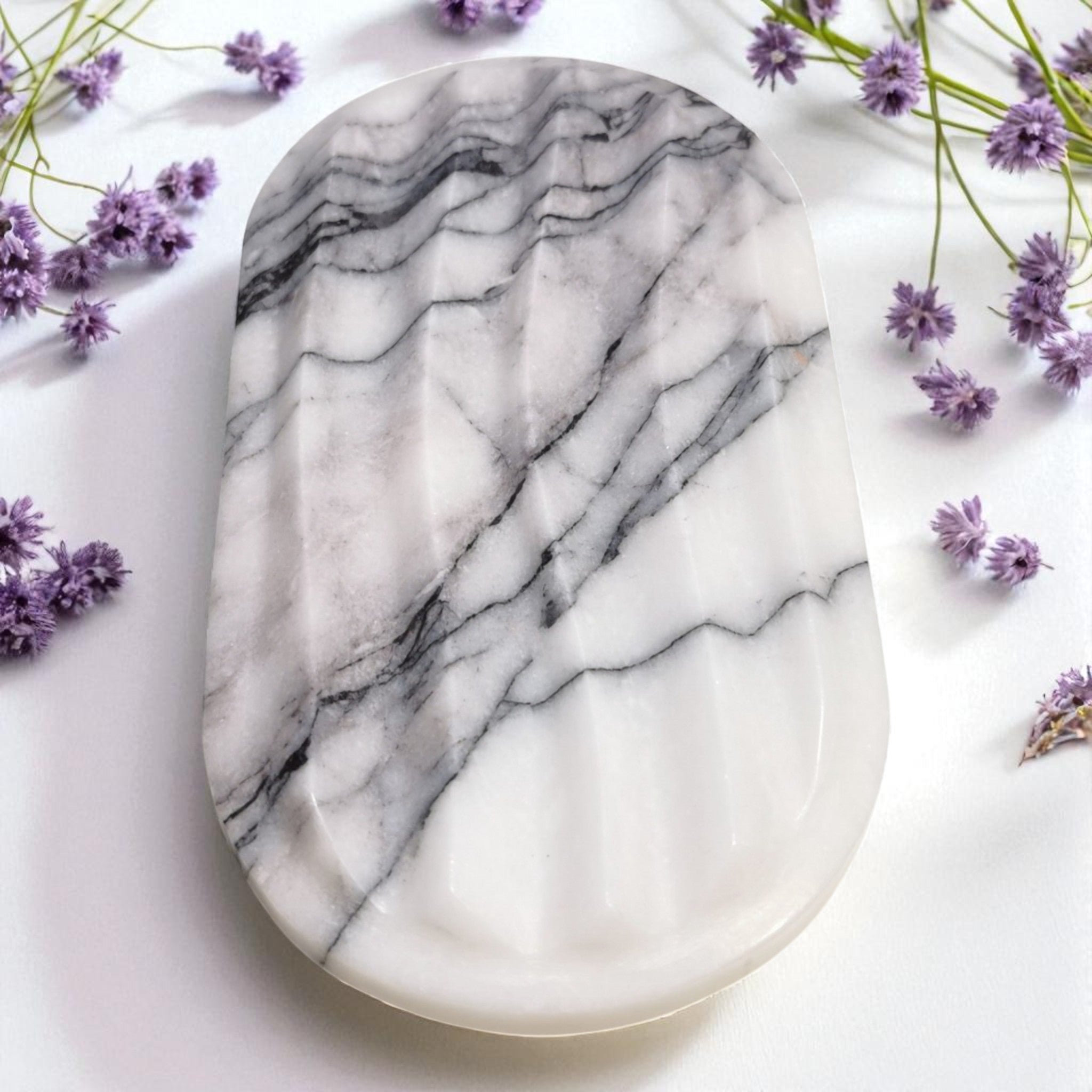 Marble-patterned stone on a white surface with purple flowers