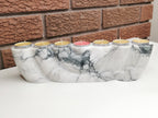 Marble-patterned candle holder with colorful candles against a brick wall.