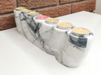 Marble-patterned candle holder with lit candles on a white surface.