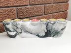 Marble-patterned candle holder with lit candles against a brick wall background