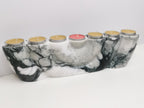 Marble-patterned candle holder with six candles on a white background