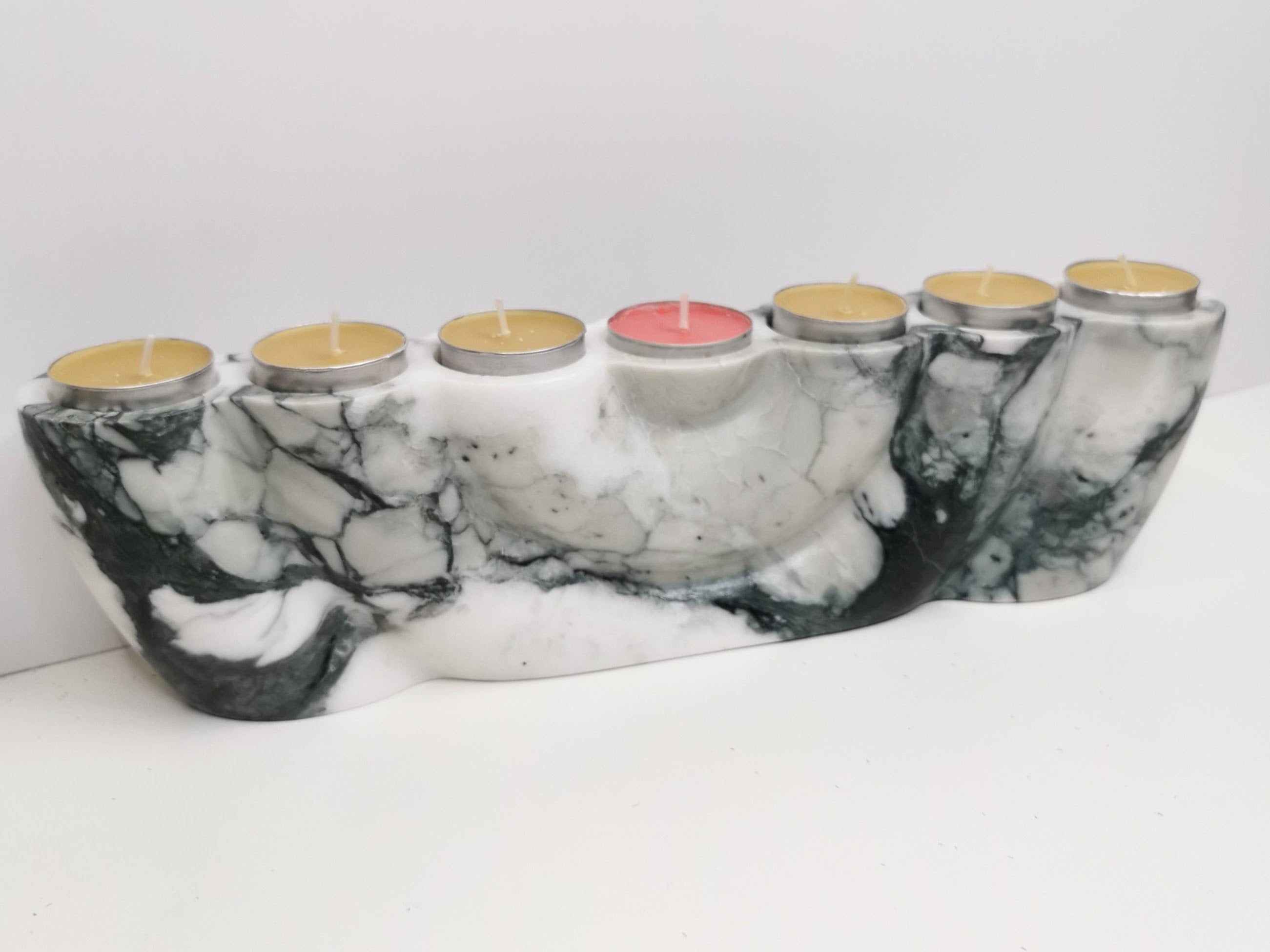 Marble-patterned candle holder with six candles on a white background