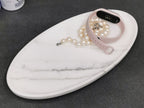 Rectangle marble jewelry tray holding a pearl necklace and a watch