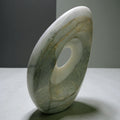 Abstract marble sculpture with smooth curved form and central void opening, polished
gray stone, contemporary luxury home decor art piece