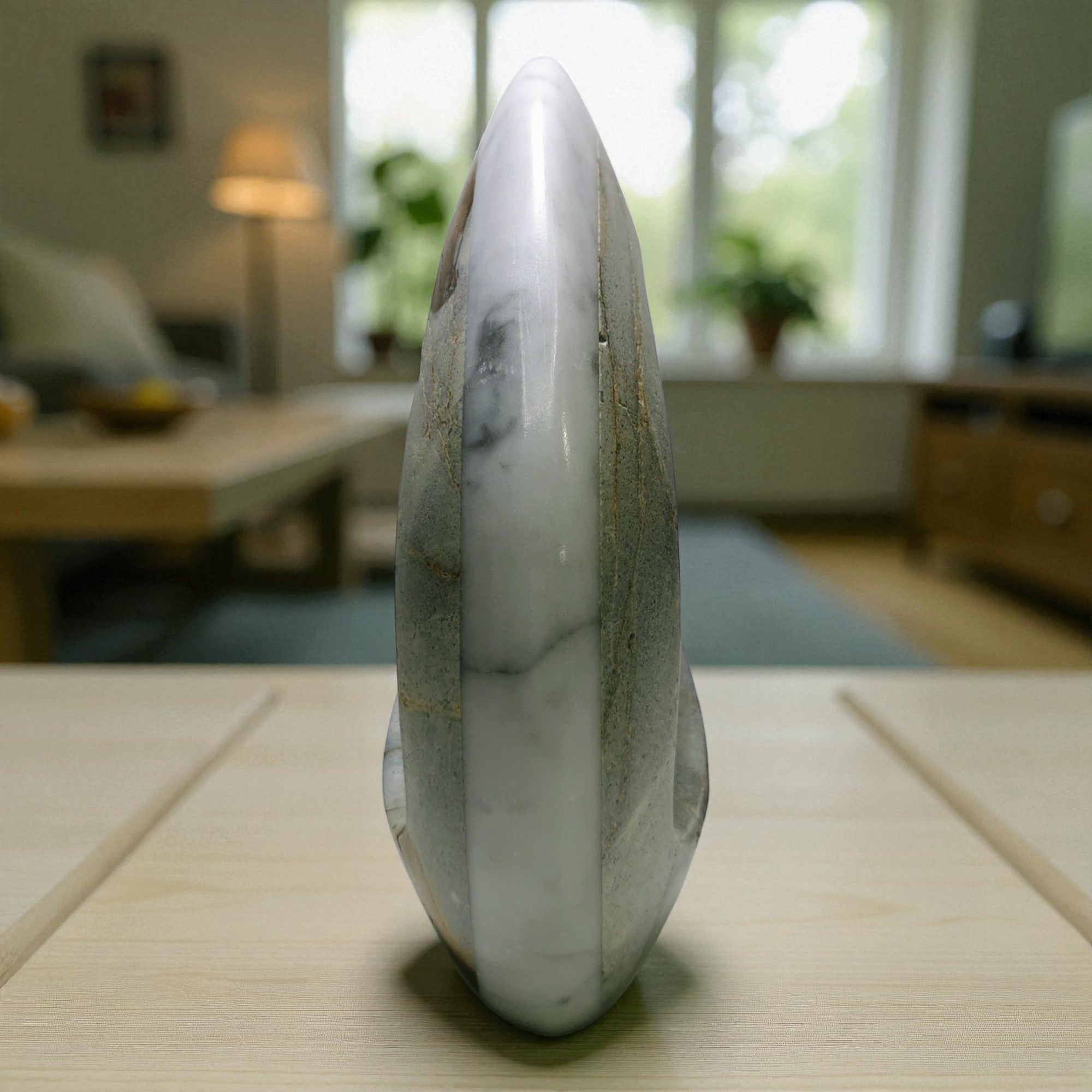 Marble-like stone sculpture on a table with a blurred indoor background