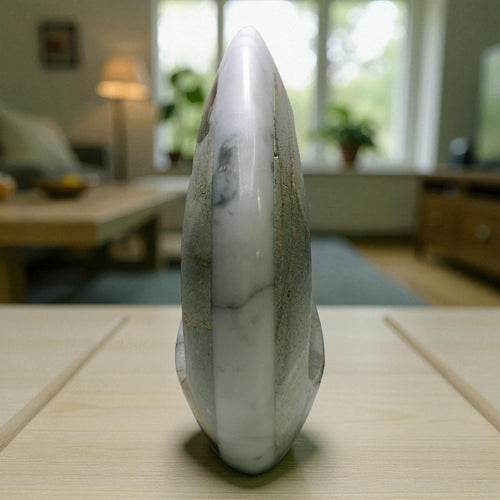 Marble-like stone sculpture on a table with a blurred indoor background