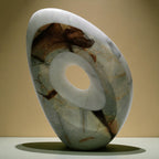 Marble-like sculpture with a central circular cutout on a beige background