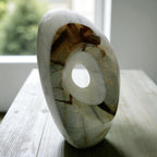 Marble-like stone with a central hole on a wooden surface