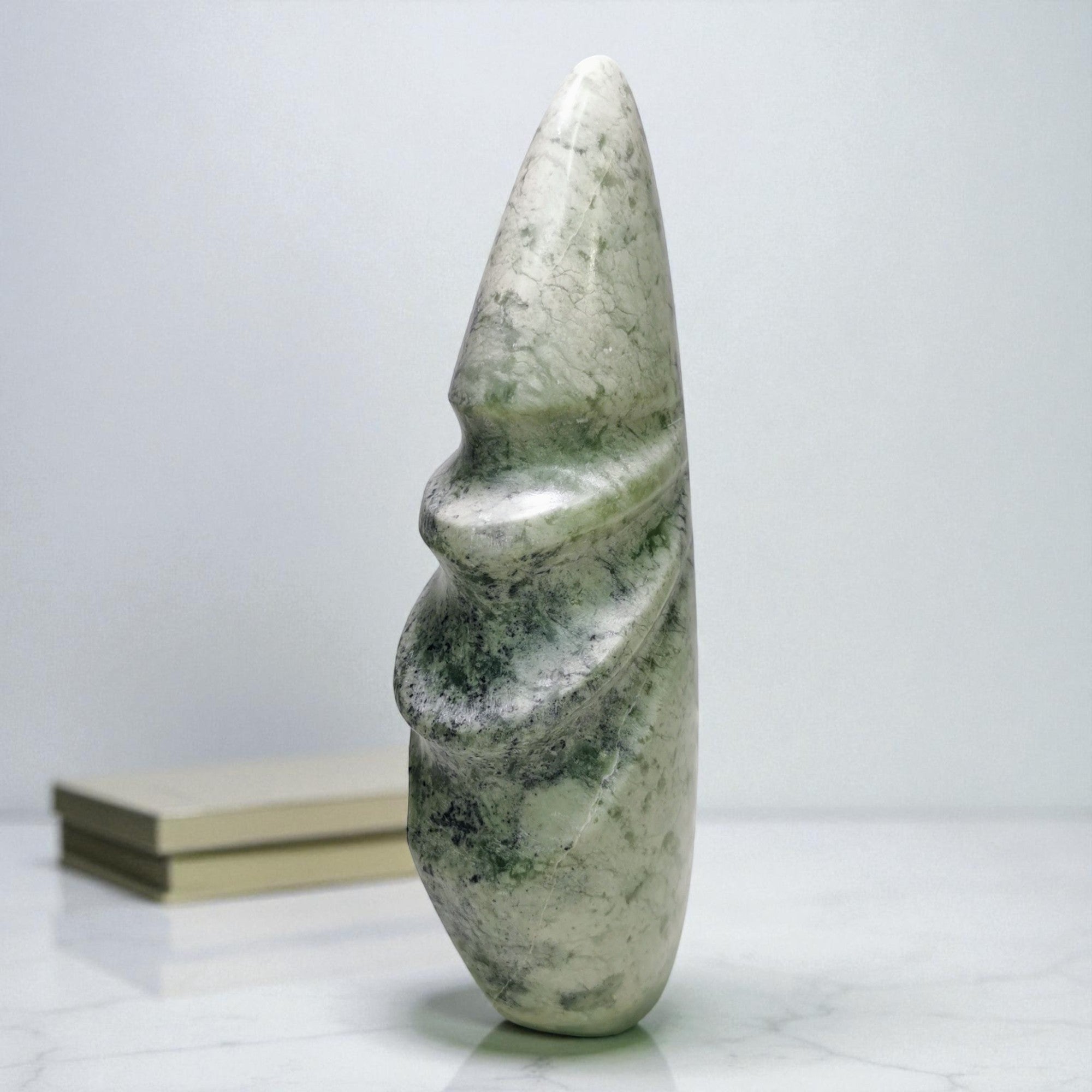 Stone sculpture of a figure on a white surface with a white background