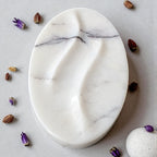 Marble-patterned oval plate on a light gray surface with small decorative items around it.