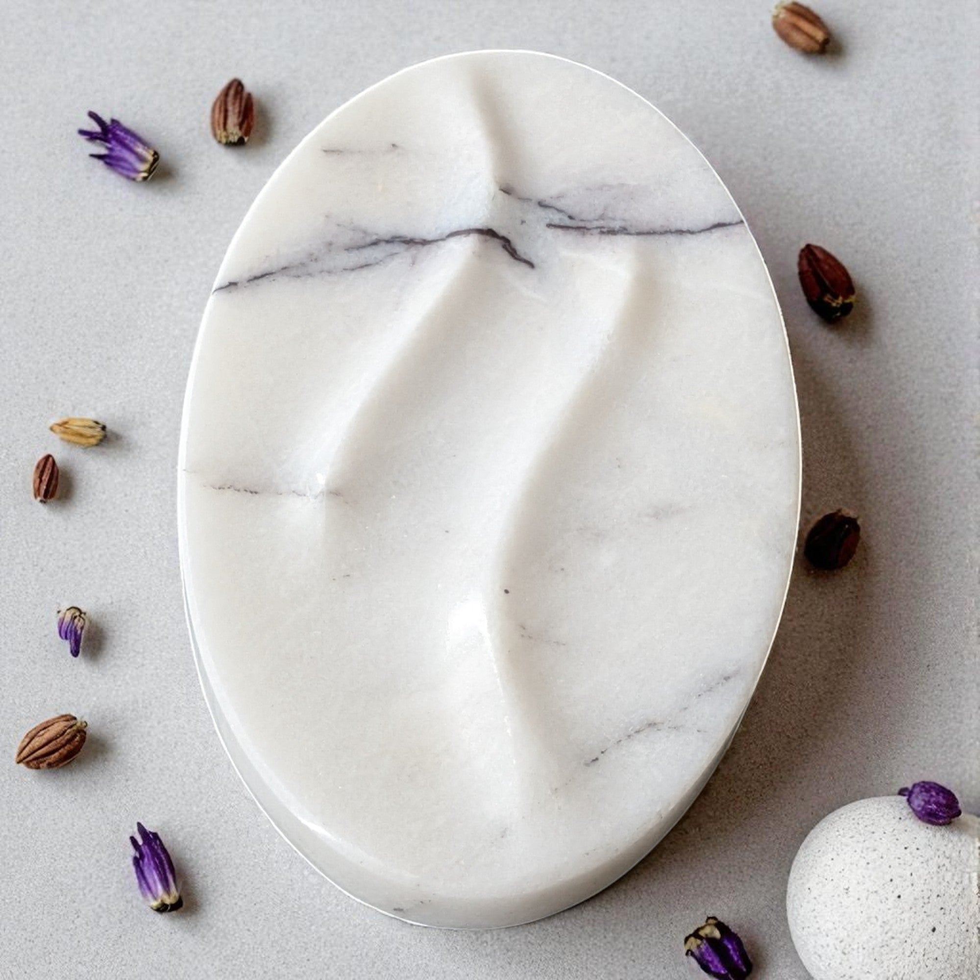 Marble-patterned oval plate on a light gray surface with small decorative items around it.
