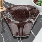 Marble-patterned soap dish on a marble surface with a plant in the background