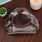 Marble-patterned stone on a wooden surface with a candle and small plant in the background