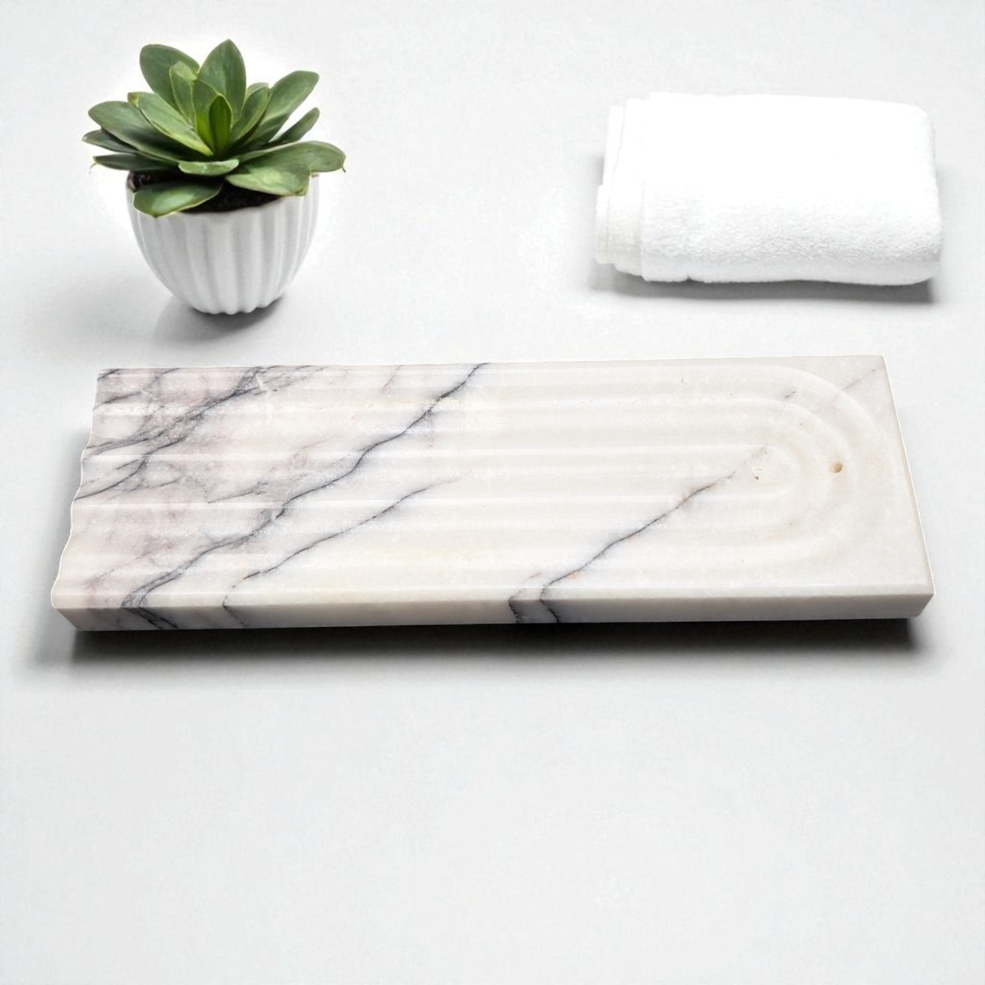 Marble-patterned tray with a potted succulent and folded towel on a white background