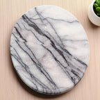 Round marble soap dish on a wooden surface with a small plant in the corner.