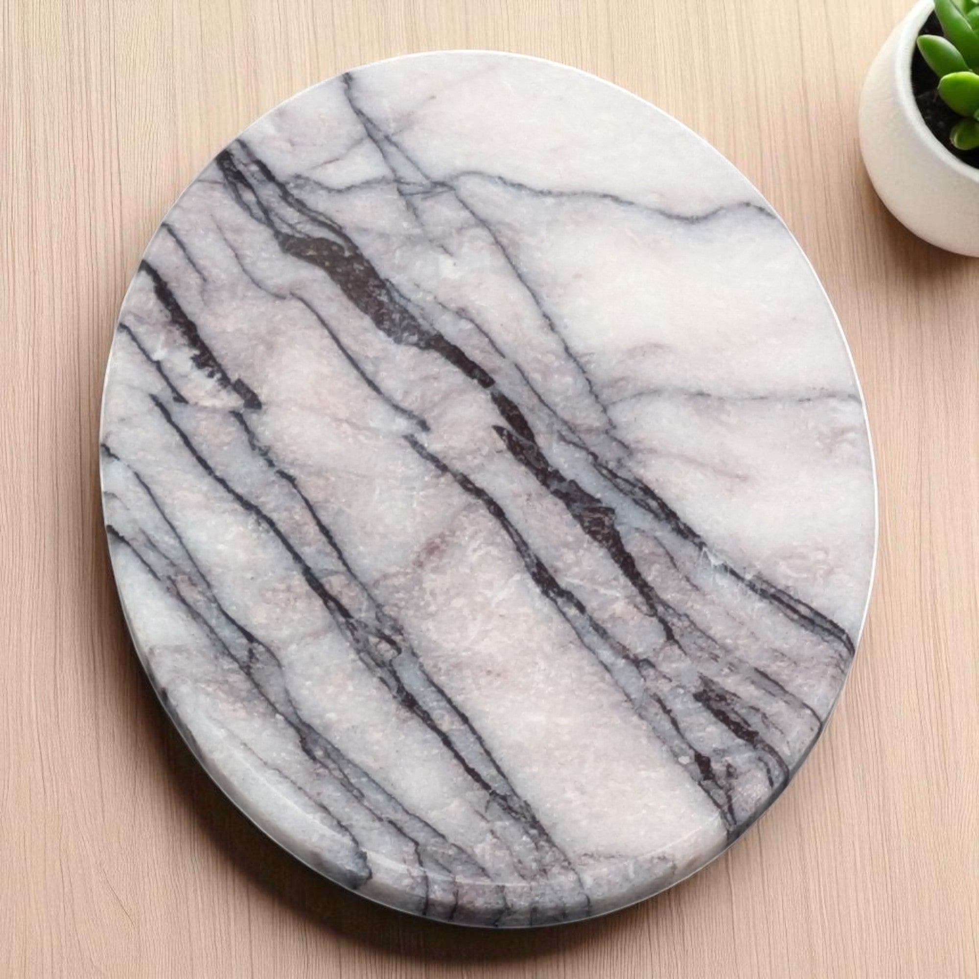 Round marble soap dish on a wooden surface with a small plant in the corner.
