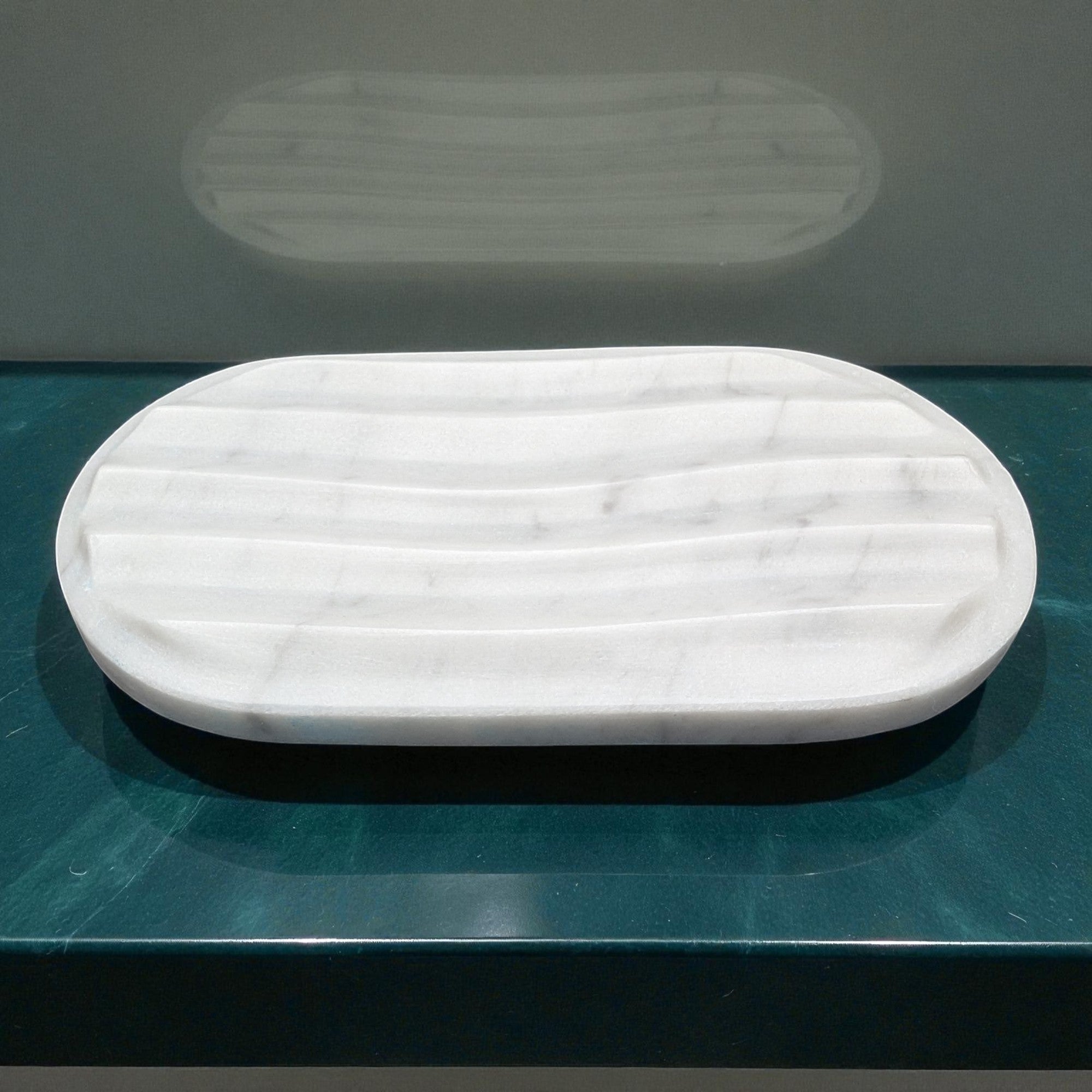 White marble tray on a teal surface with a gray background