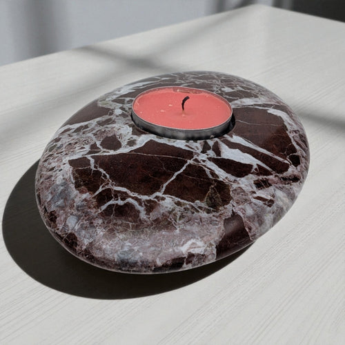 Marble-patterned stone with a red candle on a light surface