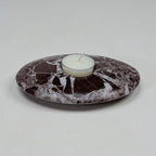 Marble-patterned candle holder with a white candle on a light gray background