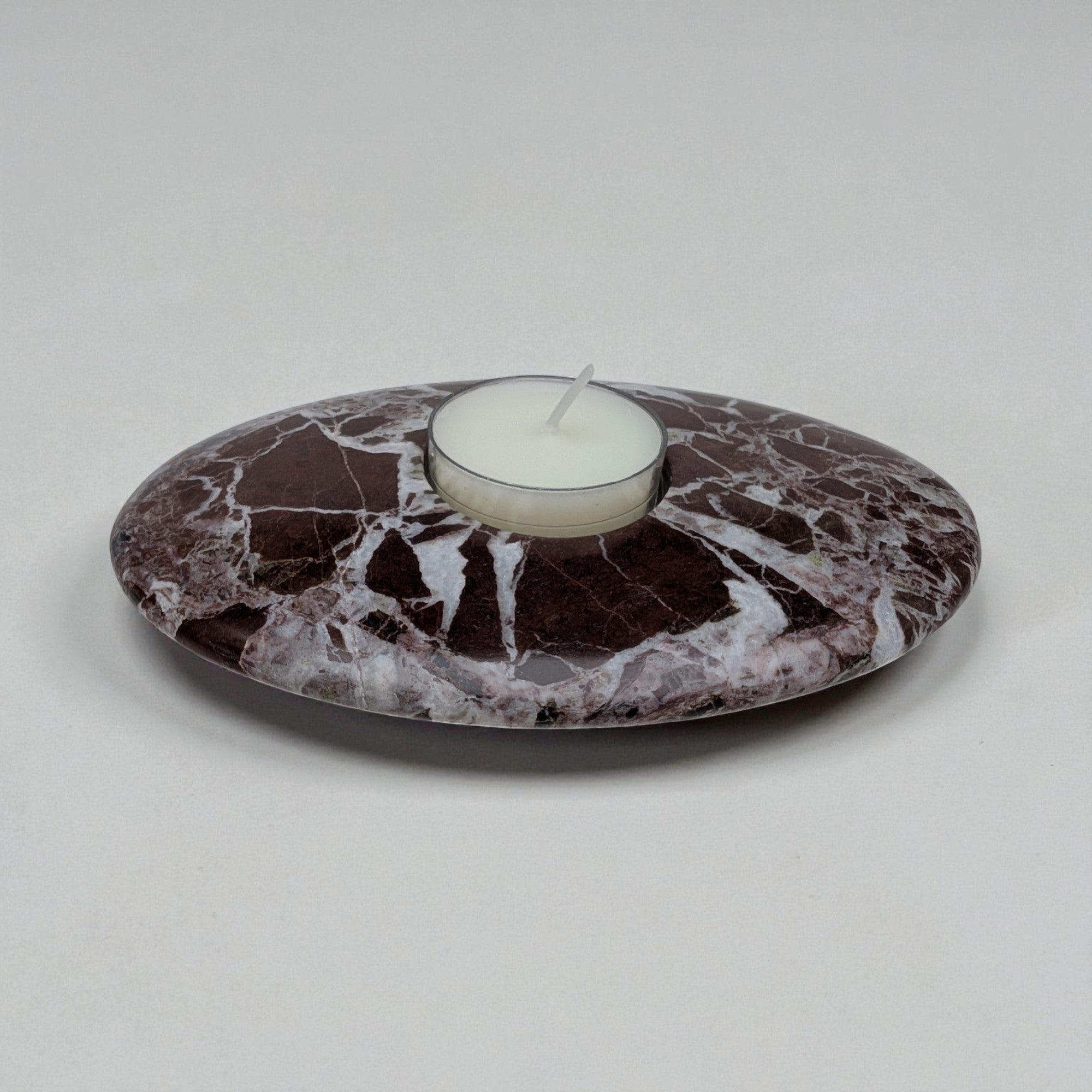 Marble-patterned candle holder with a white candle on a light gray background