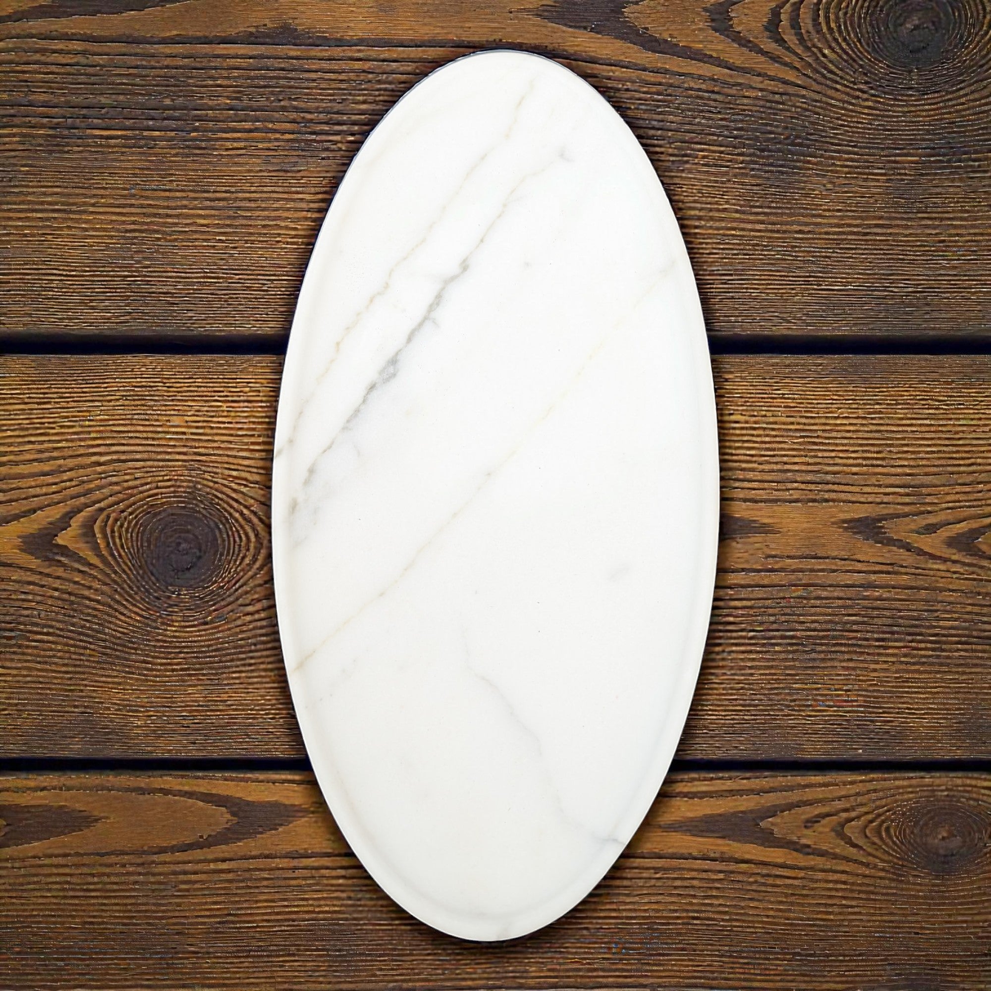 Oval-shaped marble cutting board on a wooden surface