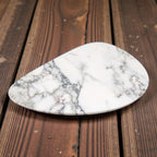 White marble jewelry tray, irregular shape, on a wooden surface