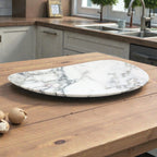 White marble jewelry tray, irregular shape, on a wooden kitchen table