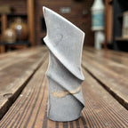 Gray stone with feather on a wooden surface