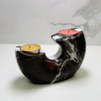 Marble-patterned candle holder with two candles on a white surface.