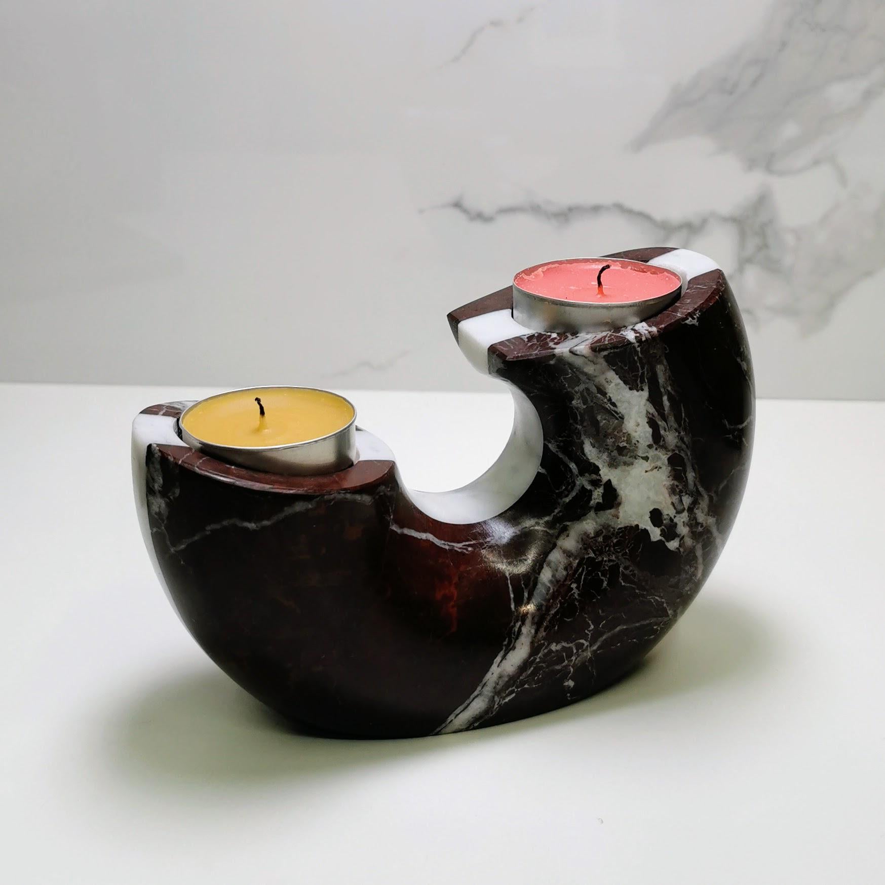 Marble-patterned candle holder with two candles on a white surface.