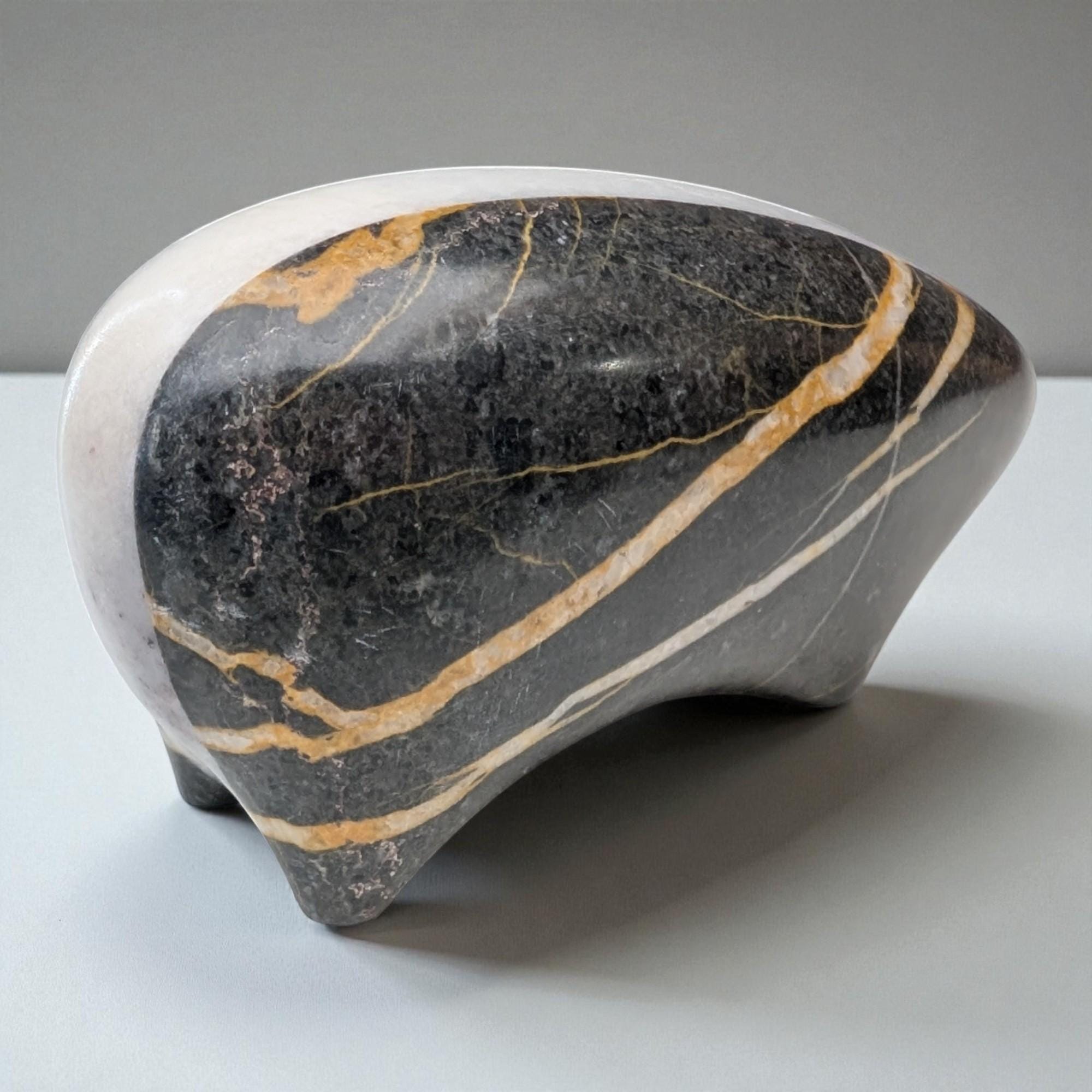 Decorative stone sculpture with black, gold, and white patterns on a gray background