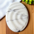 Marble-patterned plate on a wooden surface with a white cloth and green fruit in the background